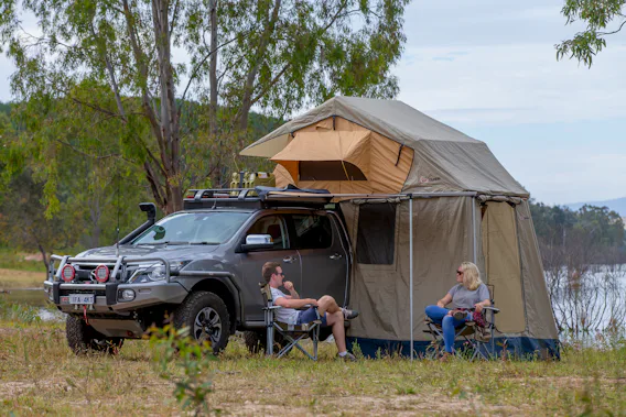 People camping, sat outside of tent on camping chairs